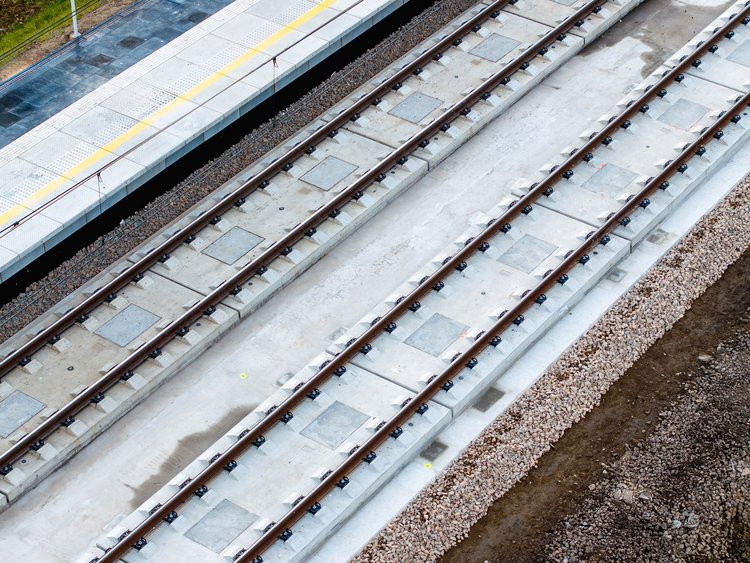 Ballastless railway tracks in two directions adjacent to a railway station in rural Poland.